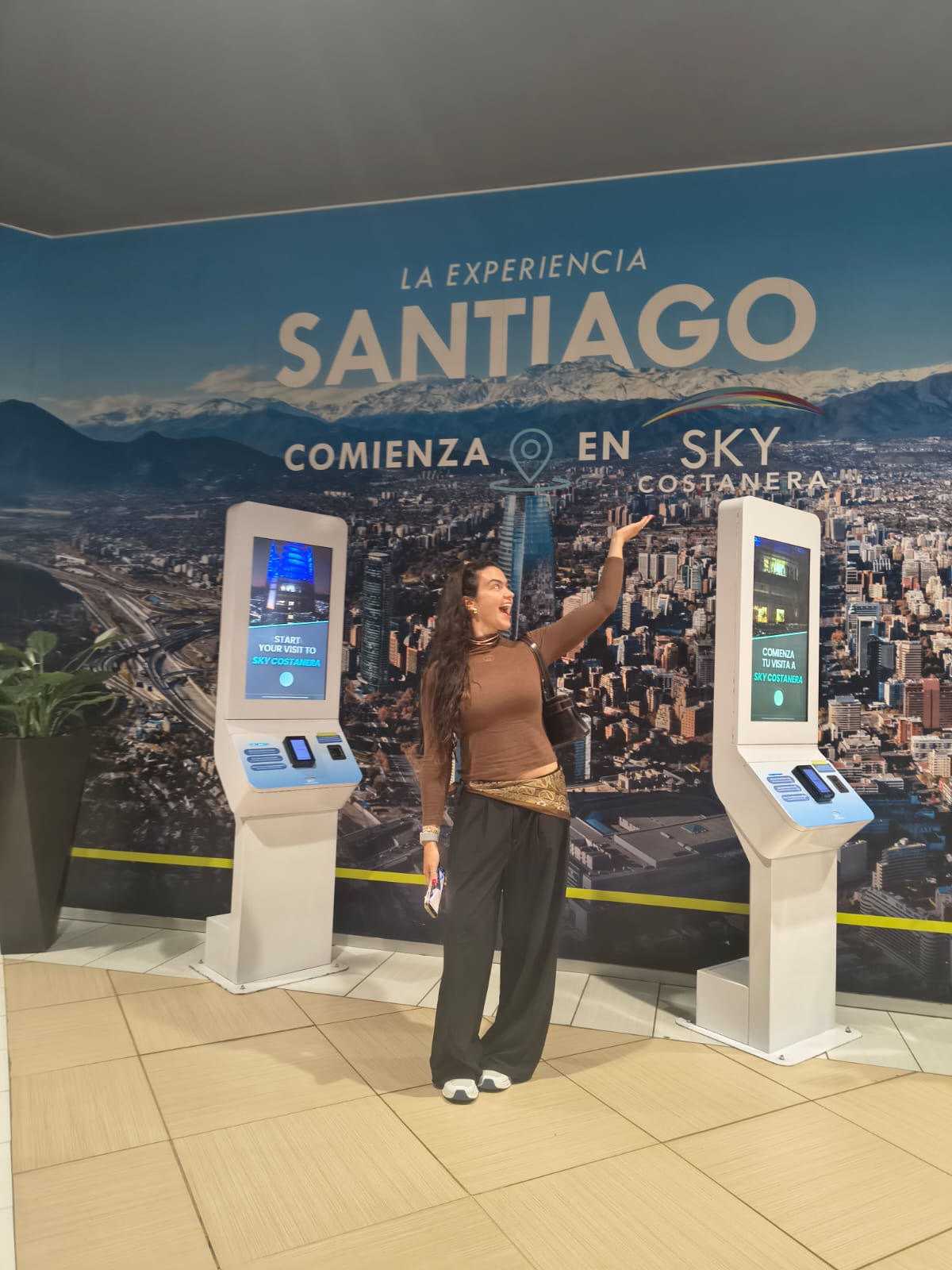 Carolina en la entrada del mirador Sky Costanera con el mural "La experiencia Santiago"