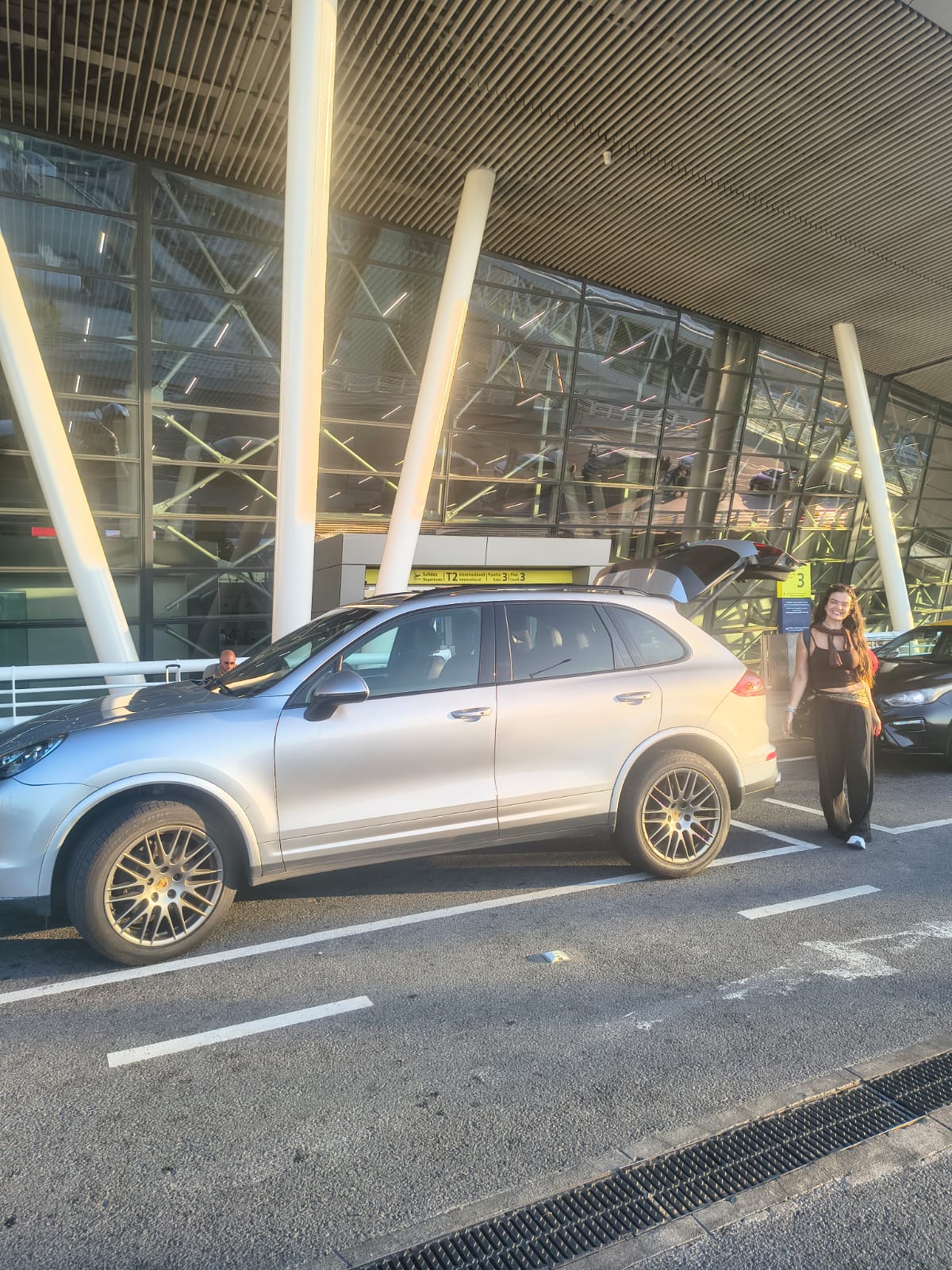 Carolina llegando al aeropuerto de Santiago junto al Porsche Cayenne en hora dorada