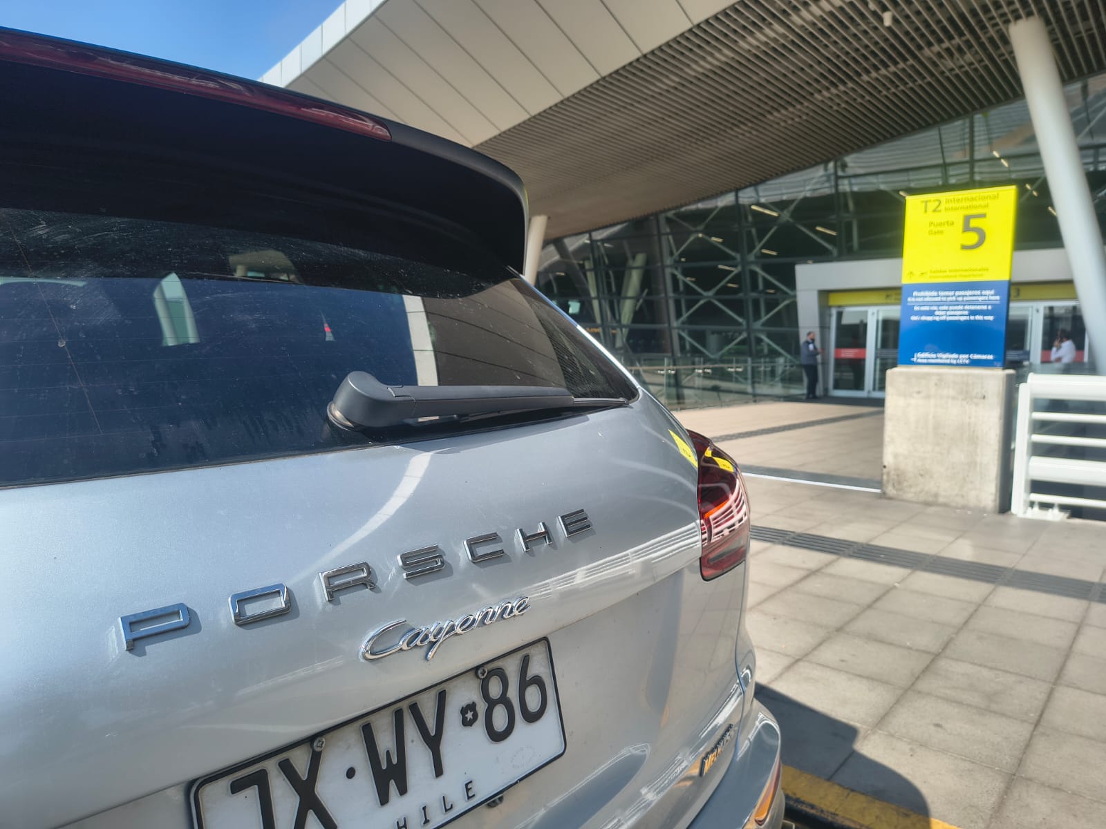 Detalle del logo Porsche Cayenne con la patente del vehículo en el aeropuerto